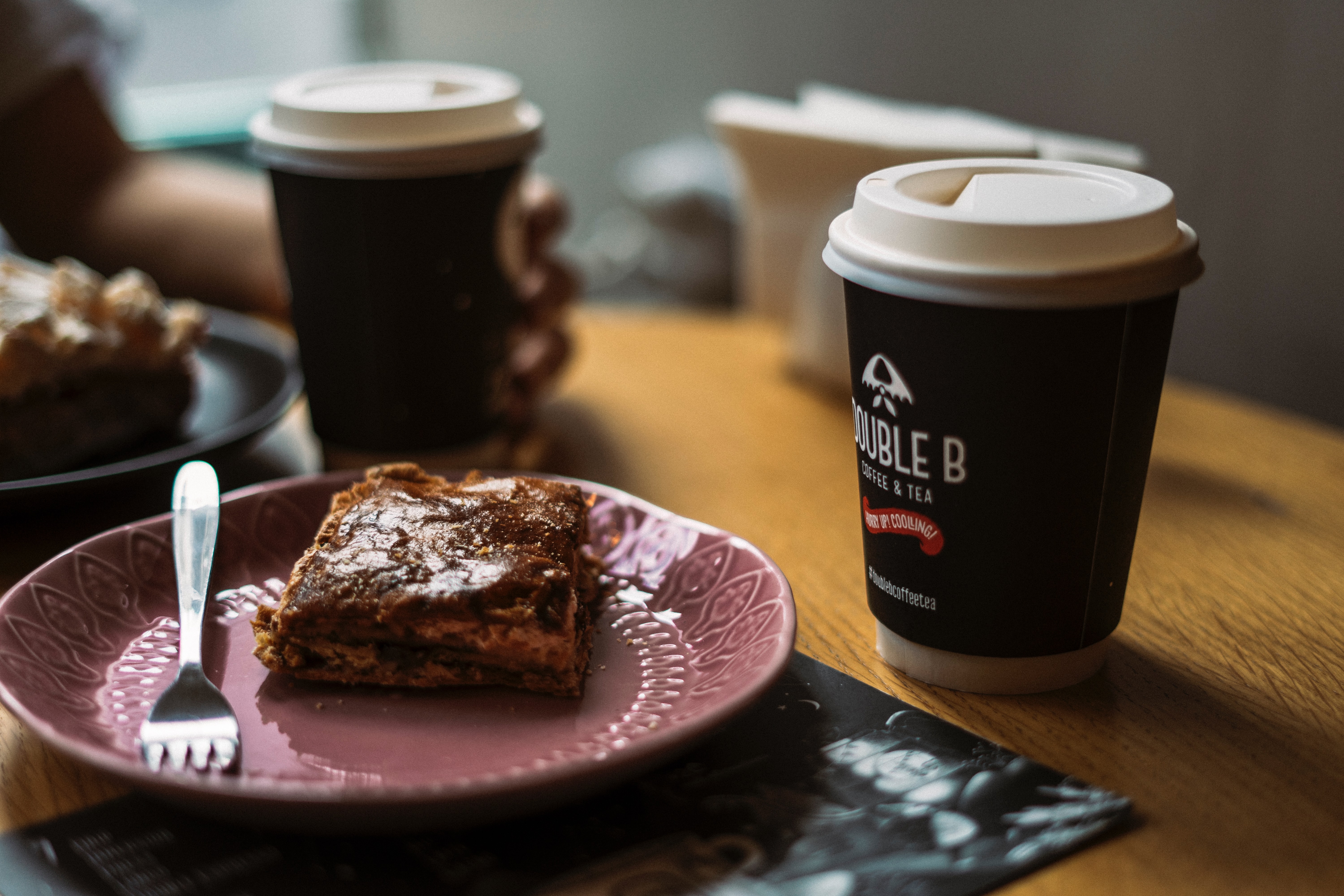 Single use coffee cups next to a slice of cake